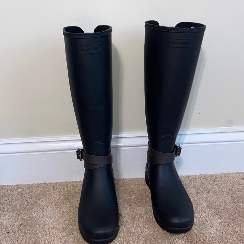 Black tall HUNTER rain boots with dark brown straps.